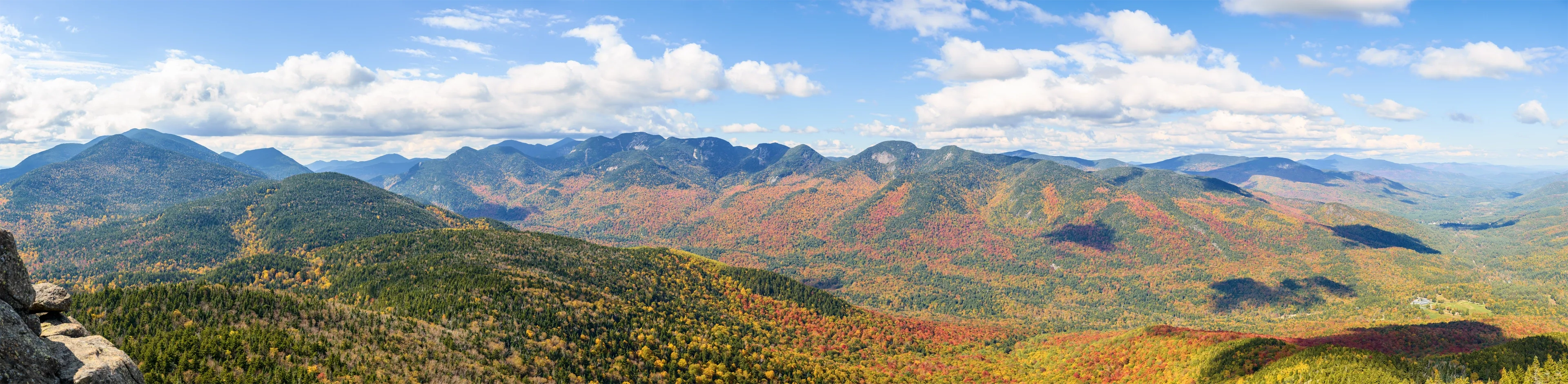 A view of Autumn High Peaks from Noonmark Summit featuring Great Range in Adirondack Mountains, NY on the Noonmark Mountain Trail during the afternoon in Autumn.