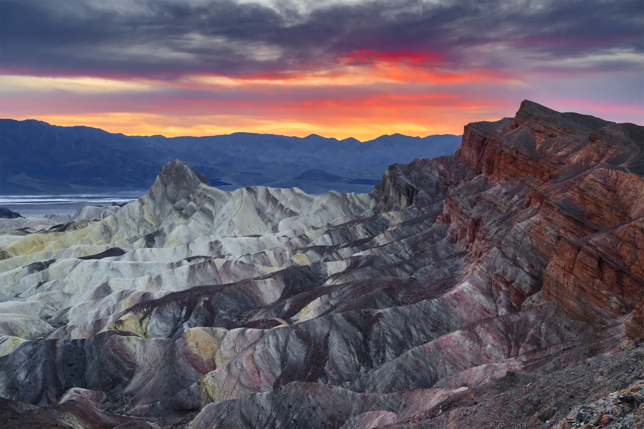 A view of Desert Fire Over Red Cathedral featuring Red Cathedral & Manly Beacon in Death Valley National Park, CA on the Golden Canyon / Red Cathedral Trail at sunset in Spring.